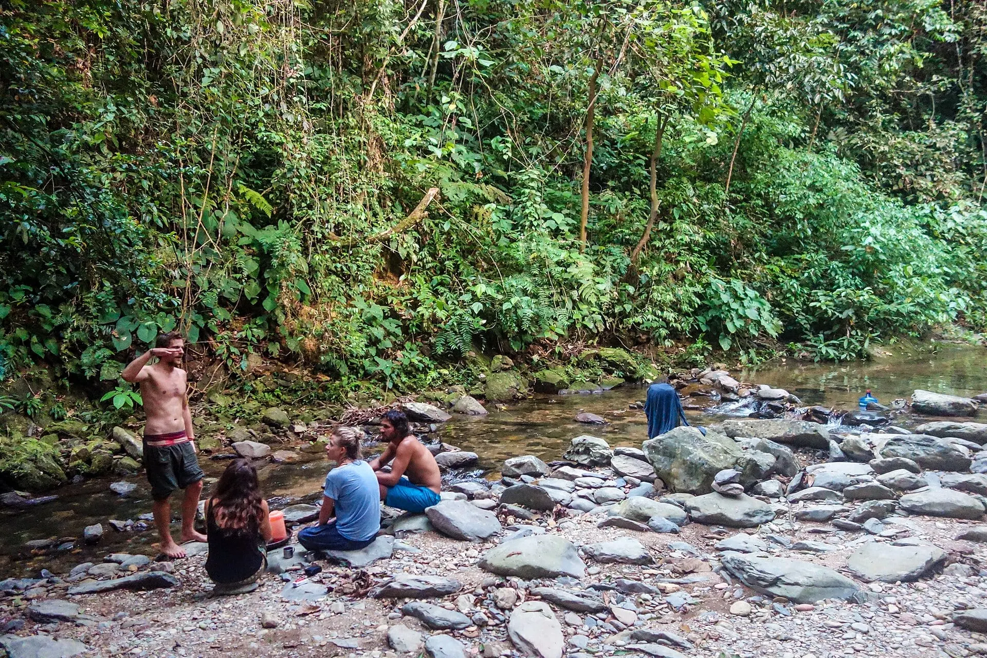 Trekkers resting on the rocks beside a jungle stream
